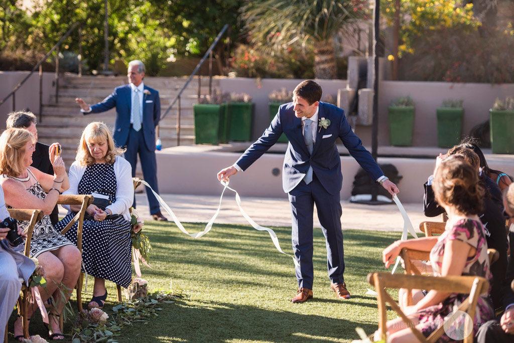 The groom removes the ribbon on the aisle as he prepares to walk down the aisle