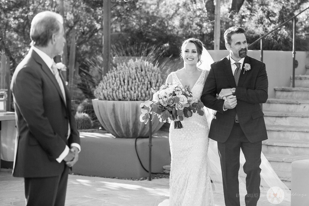 The bride walks arm in arm with her Dad as she begins her stroll down the aisle to be wedded.