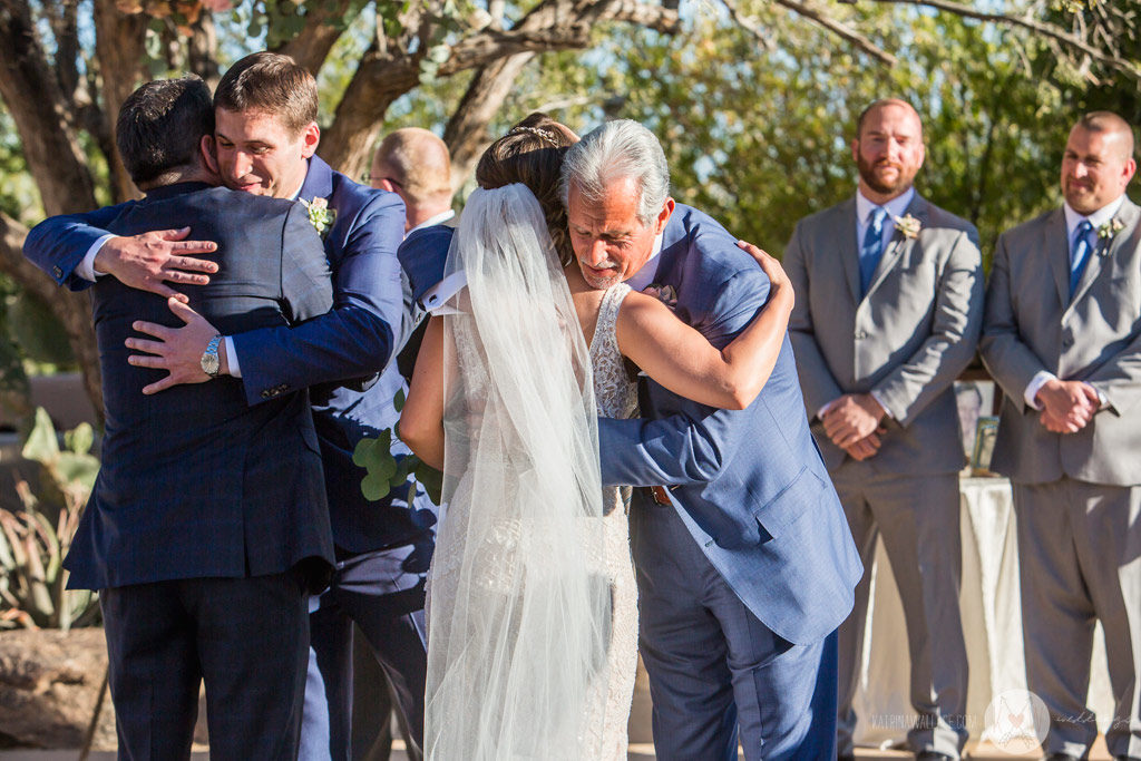 The Dads hug the bride and the groom as the ceremony begins.