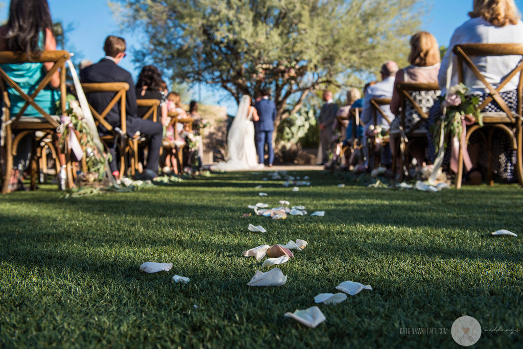 A view down the aisle from the grass, with flower petals carpeting the path.