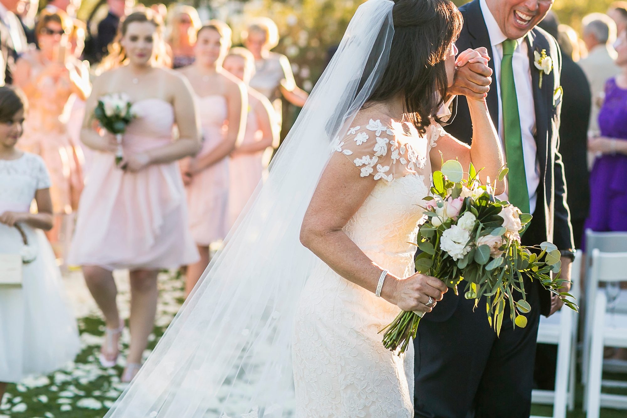 El Chorro wedding ceremony photo of a bride kissing her grooms hand as they walk away from their ceremony