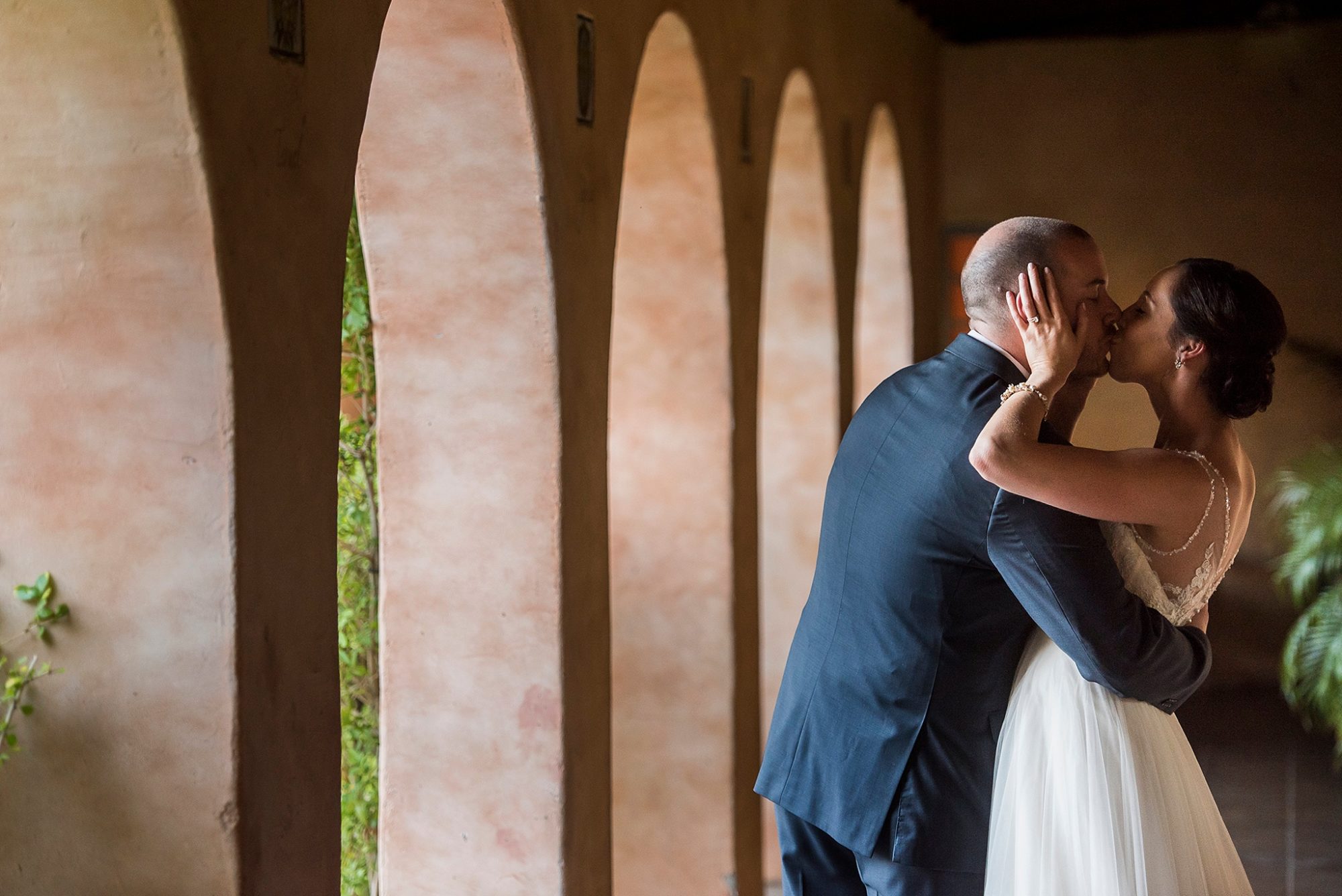 Royal Palms wedding photo of a bride kissing her groom by the arches at Royal Palms