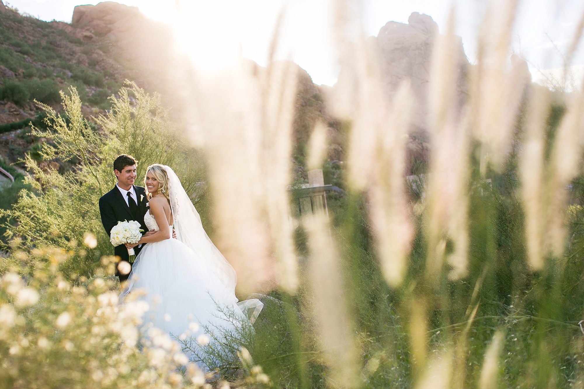 Newweds pose for a photo in the green desert at Sactuary Resort
